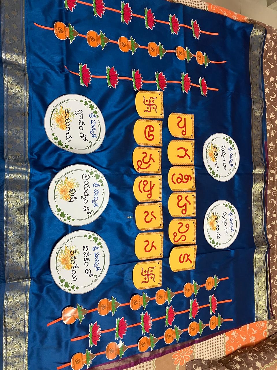 Annaprasana backdrop on a blue saree with yellow letters and round plates