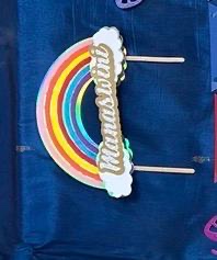 Rainbow cake topper with a name in gold on a cloud